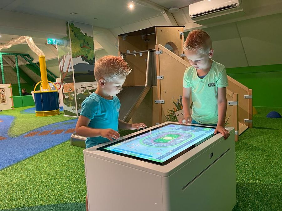 Zwei Kinder spielen an einem interaktiven Spielbildschirm auf dem Spielboden von Eetcafé Giethoorn