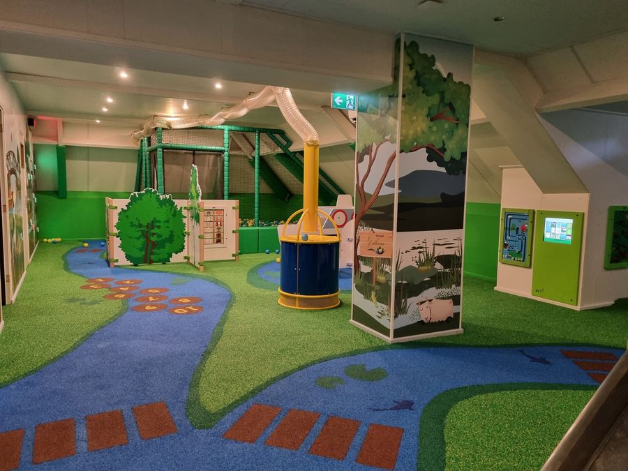 Überdachter Spielboden von Eetcafé Giethoorn mit Kunstrasen, einer Hüpfspielbahn und Klettergeräten