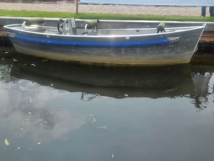 Mietsloep aus Aluminium von Haven133 mit Steuerrad, Rückenlehnen und grünen Kissen am Steg
