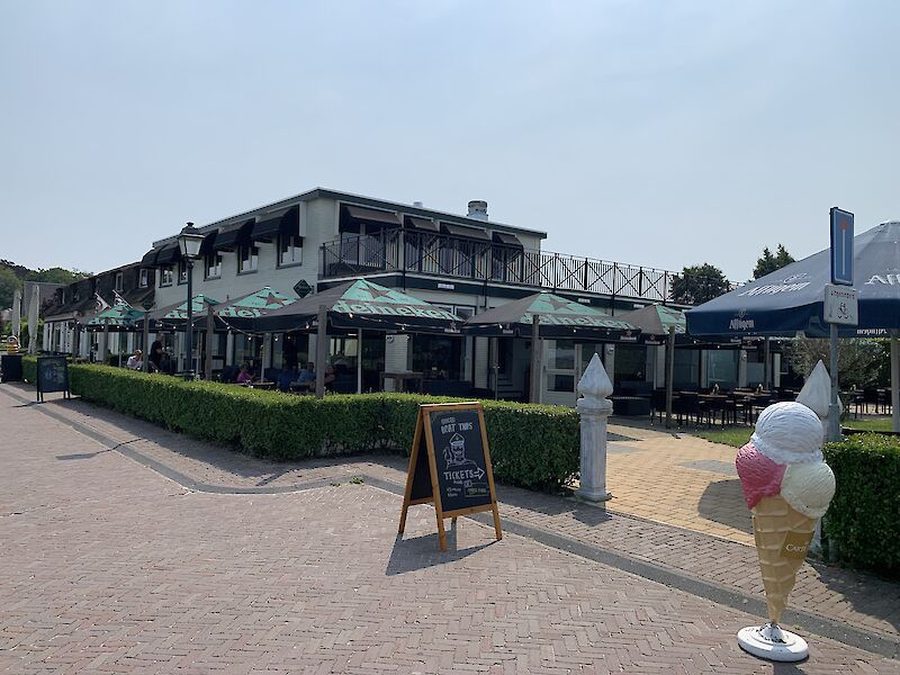 Terrasse des Grand Café Henri Willig mit Sonnenschirmen und einer großen Eiswaffel am Eingang der Eisdiele