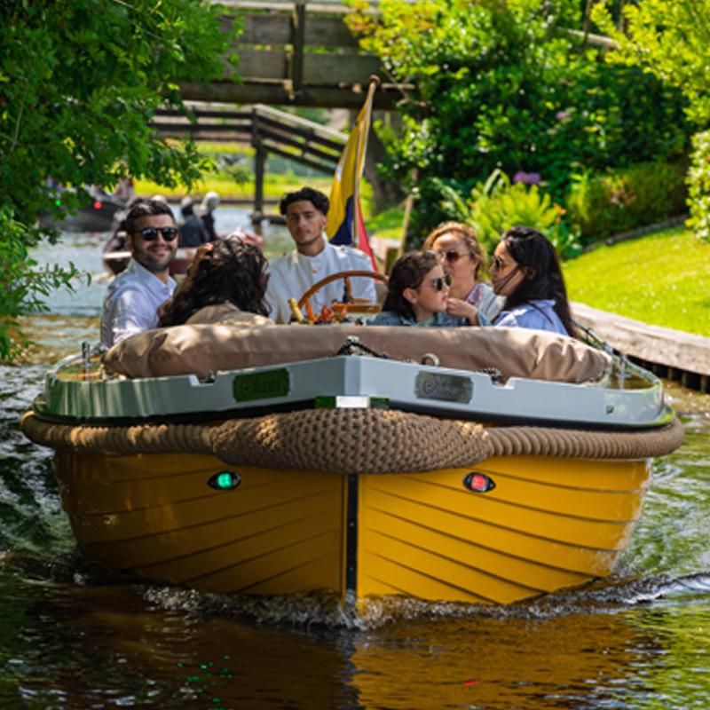 Gruppe in einer gelben Mietsloep von Hollands Venetië auf einer Gracht in Giethoorn