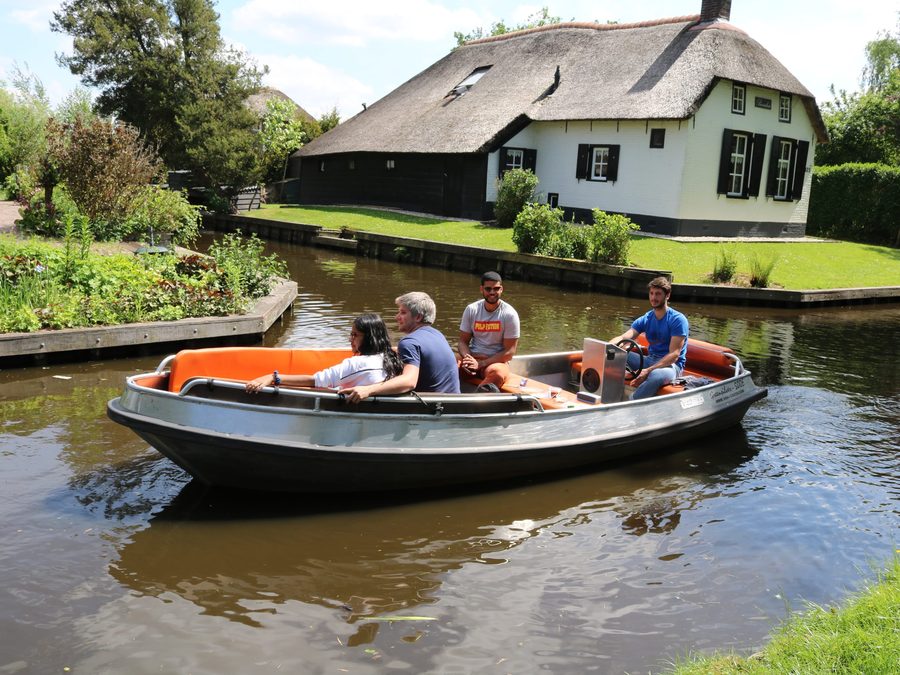 Elektrisches Mietboot mit Steuerkonsole von Koppers Giethoorn auf einer Gracht entlang eines Hofs mit Reetdach