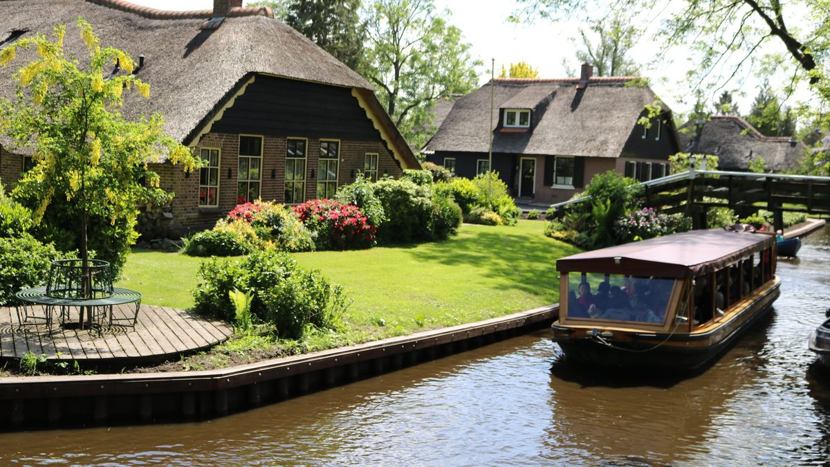 Überdachtes Rundfahrtboot von Koppers Giethoorn entlang von Höfen mit Reetdach