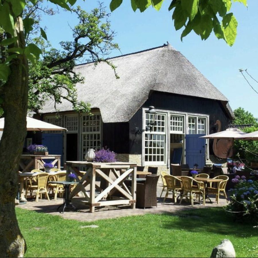 Terrasse mit Tischen und Stühlen vor dem reetgedeckten Bauernhof von De Landije in Giethoorn