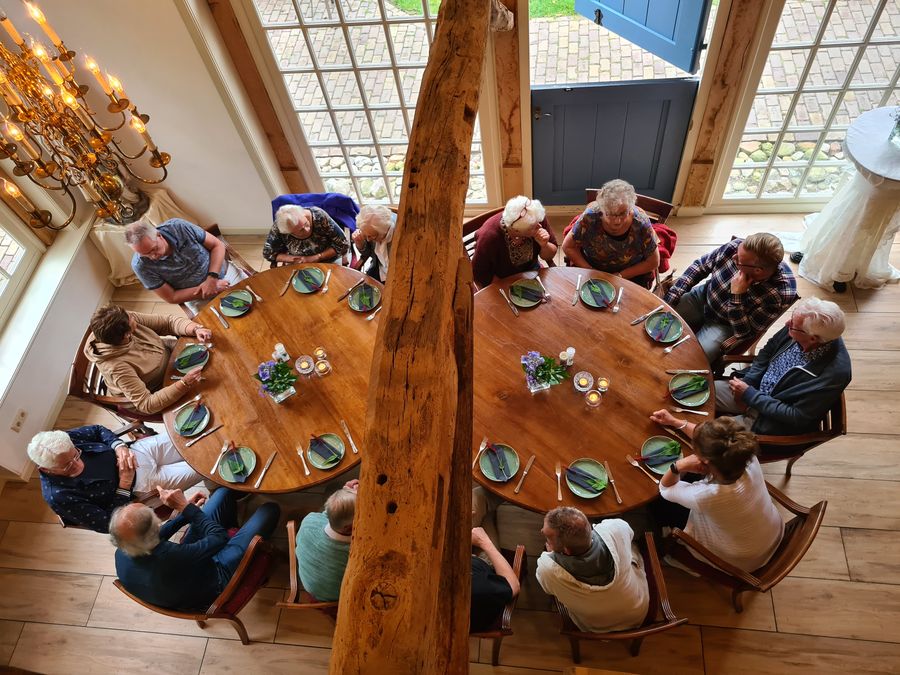 Gruppe von Gästen an runden Holztischen im Restaurant von De Landije