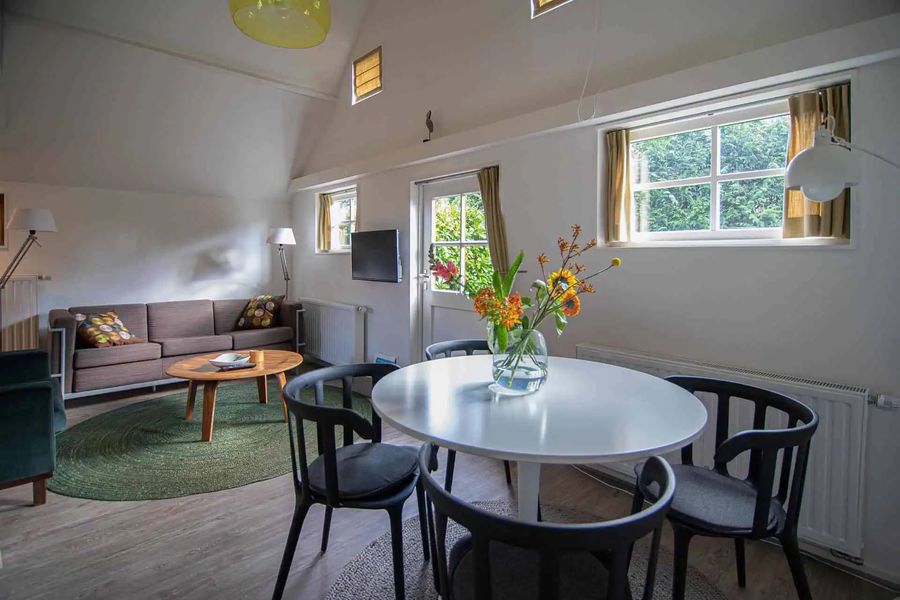 Wohnzimmer eines Ferienhäuschens von Mol Groenewegen mit Sofa, rundem Esstisch und Blick in den Garten