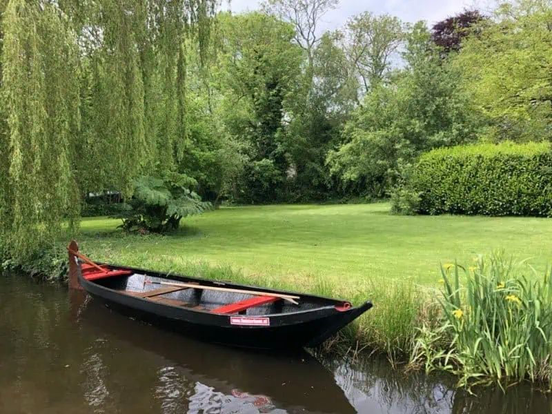 Hölzerner Punter am Ufer eines Grabens mit Trauerweiden und einer Wiese in Giethoorn