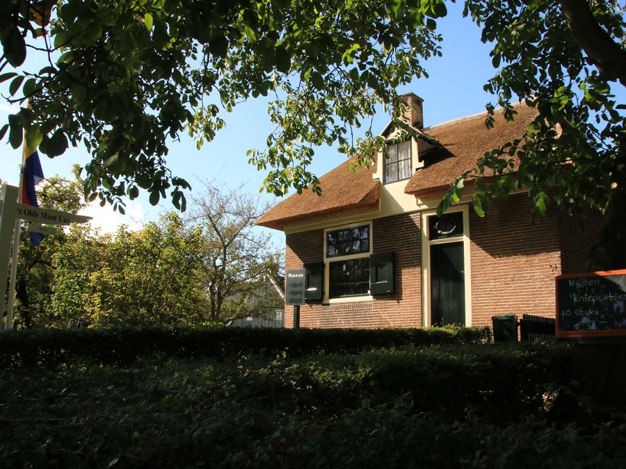 Backsteinvorderhaus des Museumsbauernhofs am Binnenpad, hinter einer Hecke und unter Bäumen