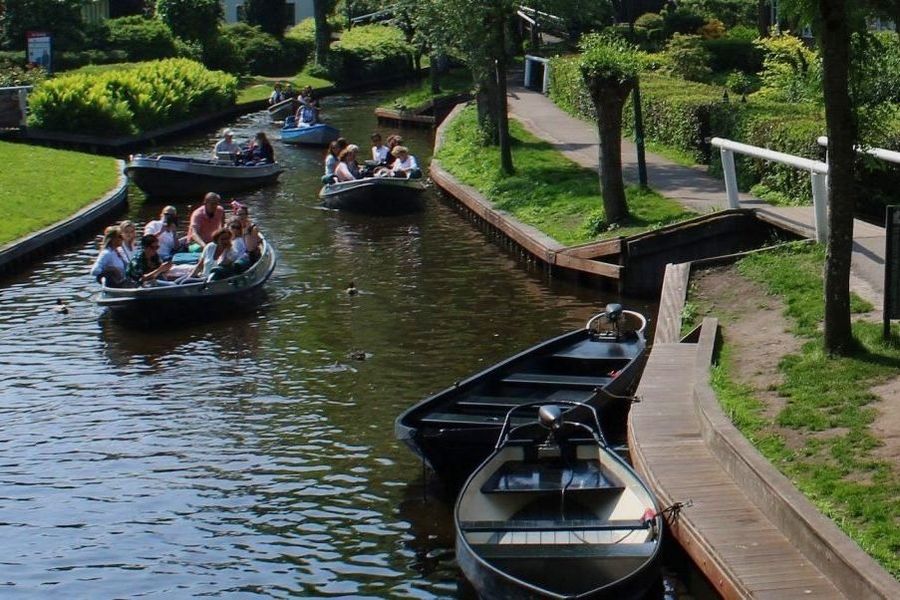 Flüsterboote mit Besuchern auf der Dorfgracht am Steg am Binnenpad in Giethoorn