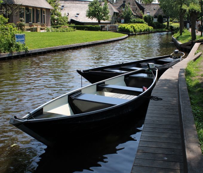 Zwei hölzerne Punter an einem Steg an einer Gracht in Giethoorn