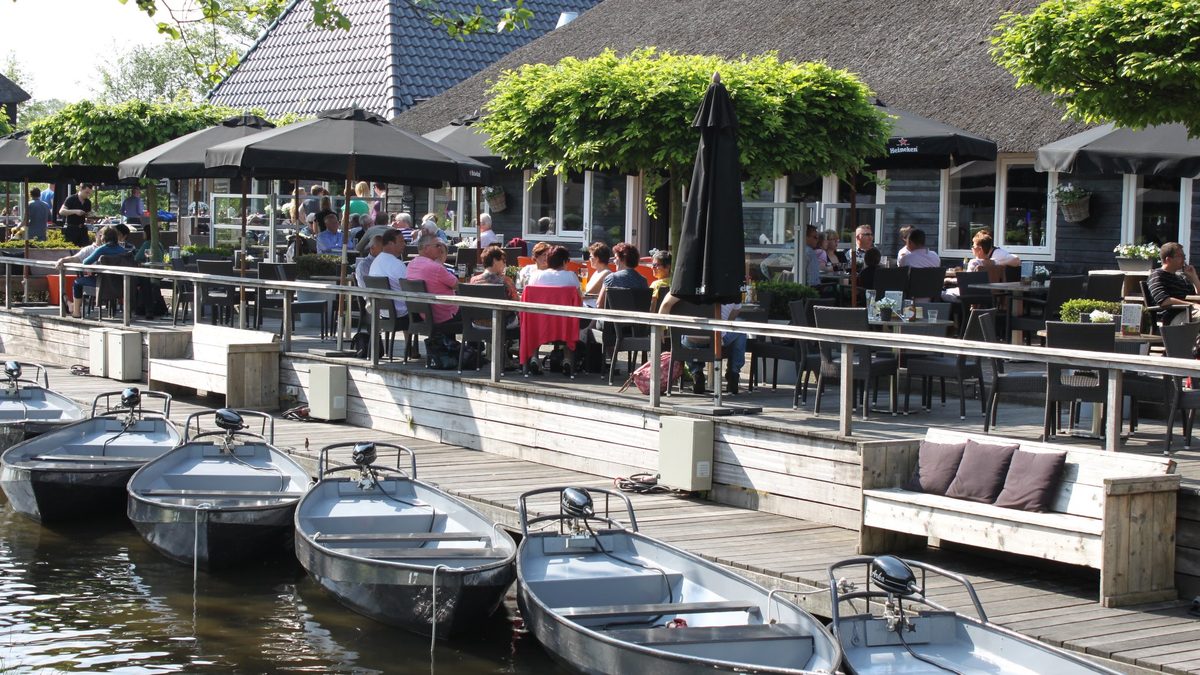Terrace of Restaurant De Grachthof on the village canal in Giethoorn, with rental boats at the quay
