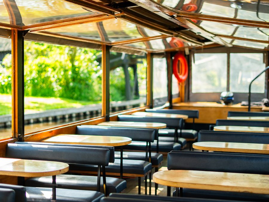 Inside the De Grachthof tour boat with benches, small tables and a glass roof