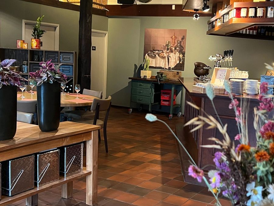 Innenraum von Restaurant 141 mit Fliesenboden, Holzbalken, einer Bar und frischen Blumen