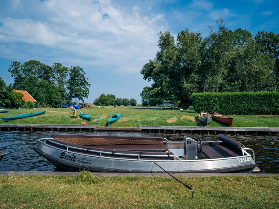 Mietsloep von Smit Giethoorn am Rand einer Fahrrinne, mit Kanus am Ufer
