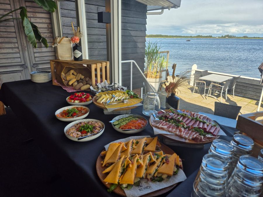 Lunchbuffet mit Brötchen, Salaten und Aufschnitt auf einem Tisch am Wasser von Smit’s Paviljoen