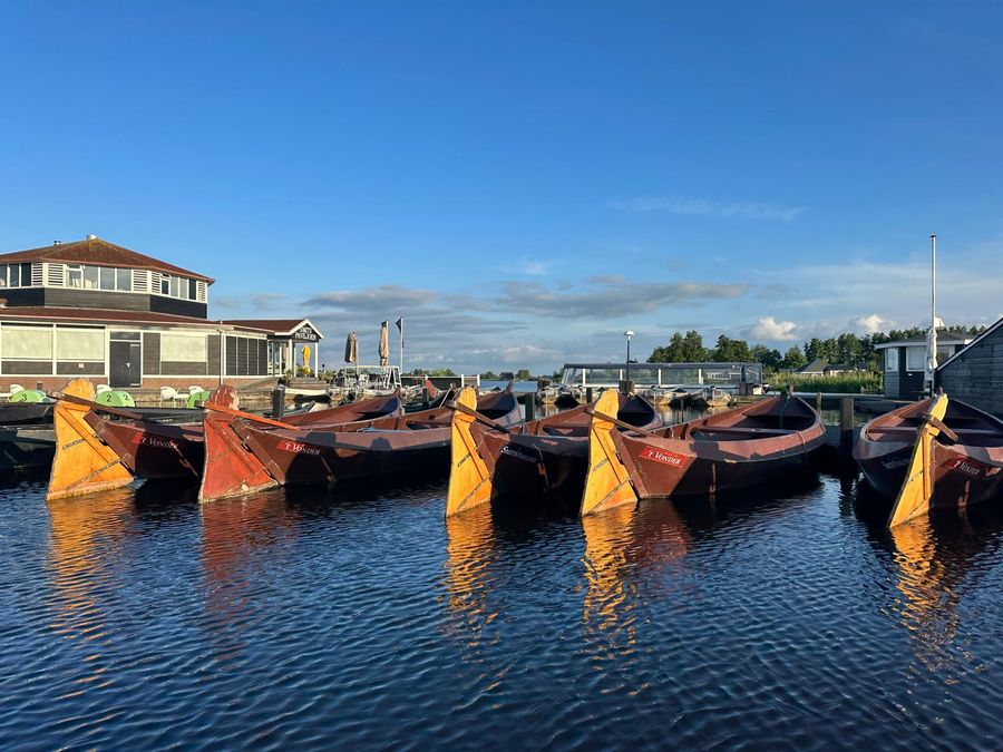 Reihe hölzerner Punter mit aufgerollten Segeln im Hafen von Smit’s Paviljoen