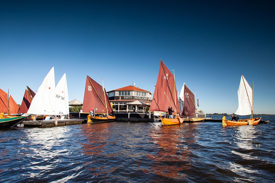 Segelpunter mit roten und weißen Segeln auf dem Bovenwijde vor Smit’s Paviljoen