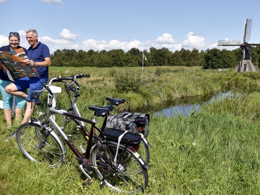 Zwei Radfahrer mit einer Karte neben ihren Fahrrädern in der Polderlandschaft bei Giethoorn