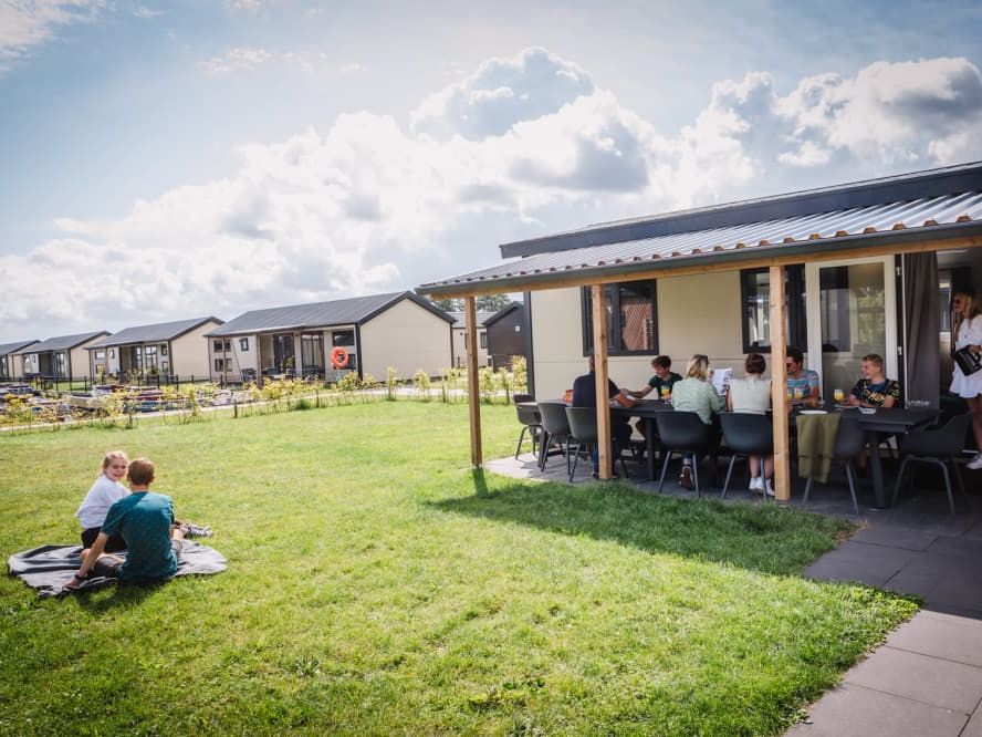 Gäste einer Gruppe am Tisch auf der überdachten Terrasse einer Gruppenunterkunft im Vakantiepark Giethoorn