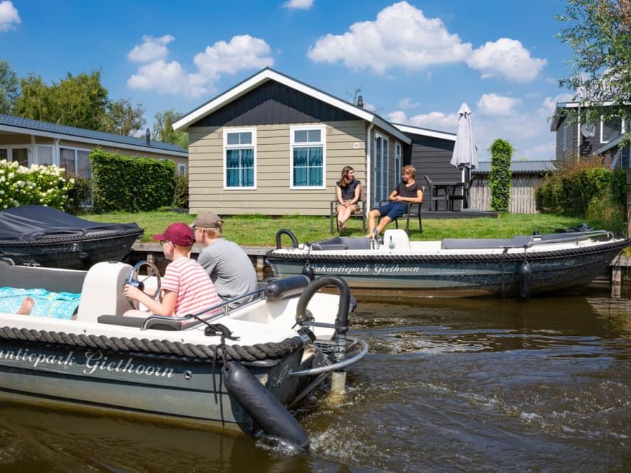 Familie in einer Sloep von Vakantiepark Giethoorn auf dem Wasser entlang der Ferienhäuser