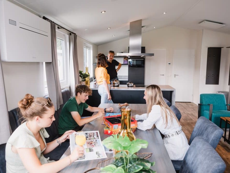 Gäste im hellen Wohnzimmer mit offener Küche eines Ferienhauses im Vakantiepark Giethoorn