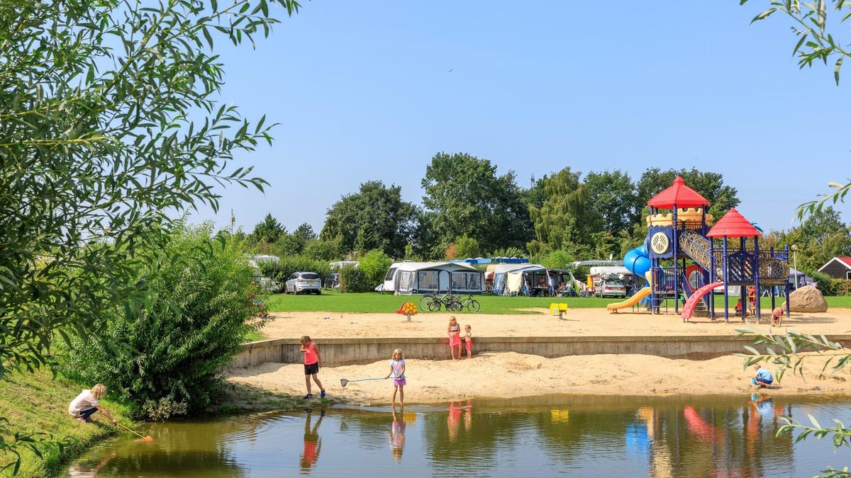 Small beach by the pond with play equipment and camping field at Vakantiepark 't Akkertien in Vollenhove