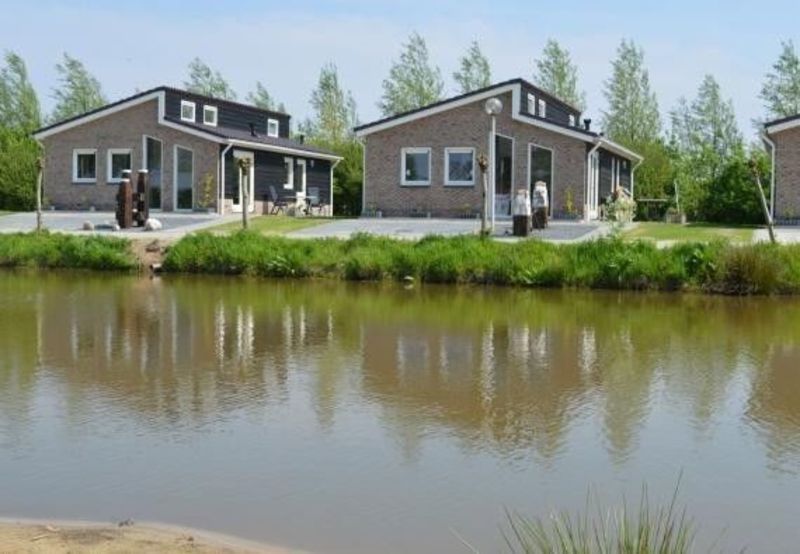 Fishermen's houses with grey facades beside a pond at Vakantiepark 't Akkertien