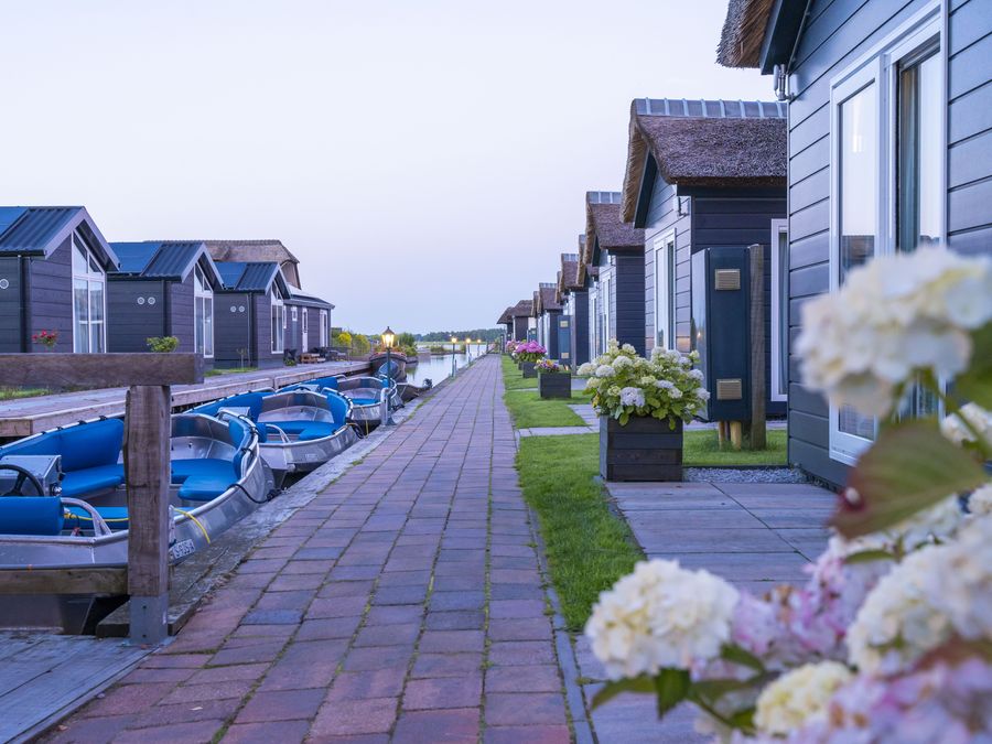 Path along the chalets of Waterpark Giethoorn with rental boats at the quay