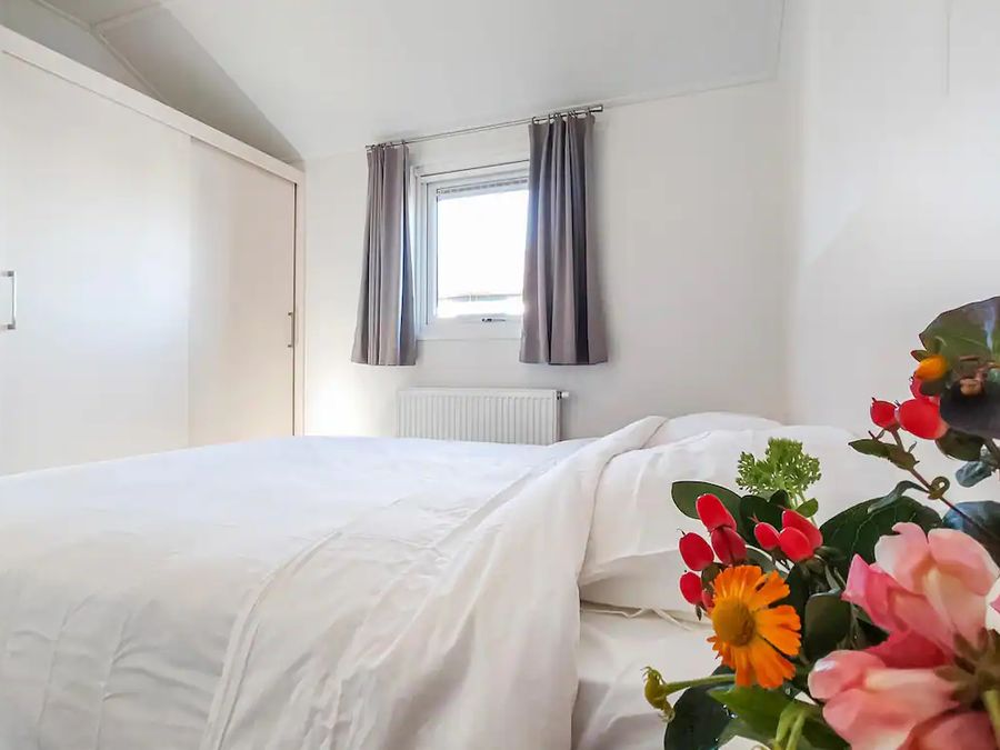 Bedroom with made bed and a bunch of flowers in a chalet at Waterpark Giethoorn