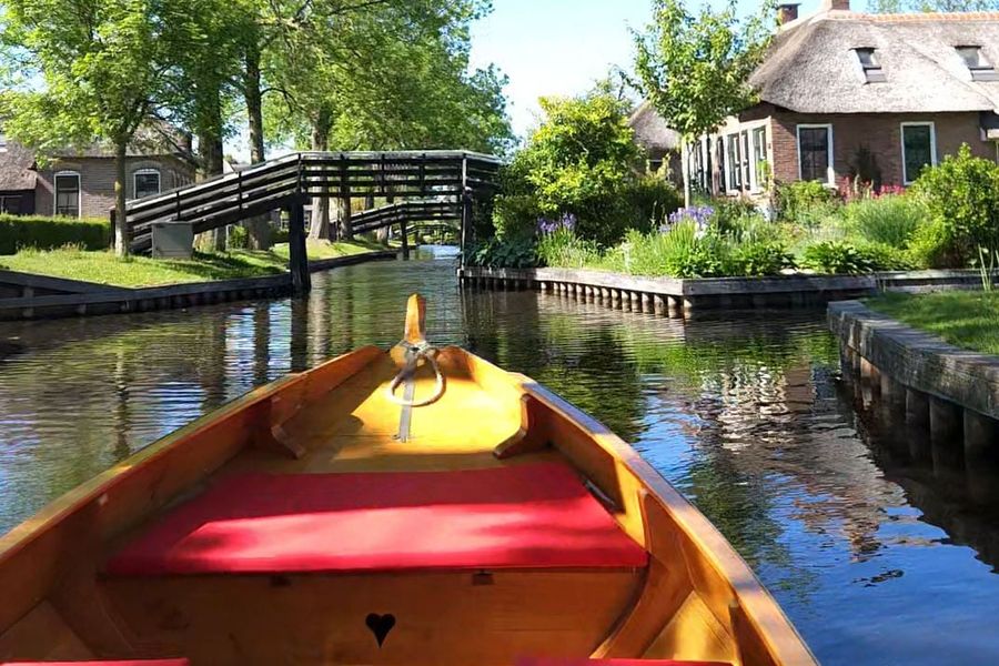 Bug eines hölzernen Punters auf der Gracht von Giethoorn-Noord, mit einer kleinen Holzbrücke und einem Reetdachhof