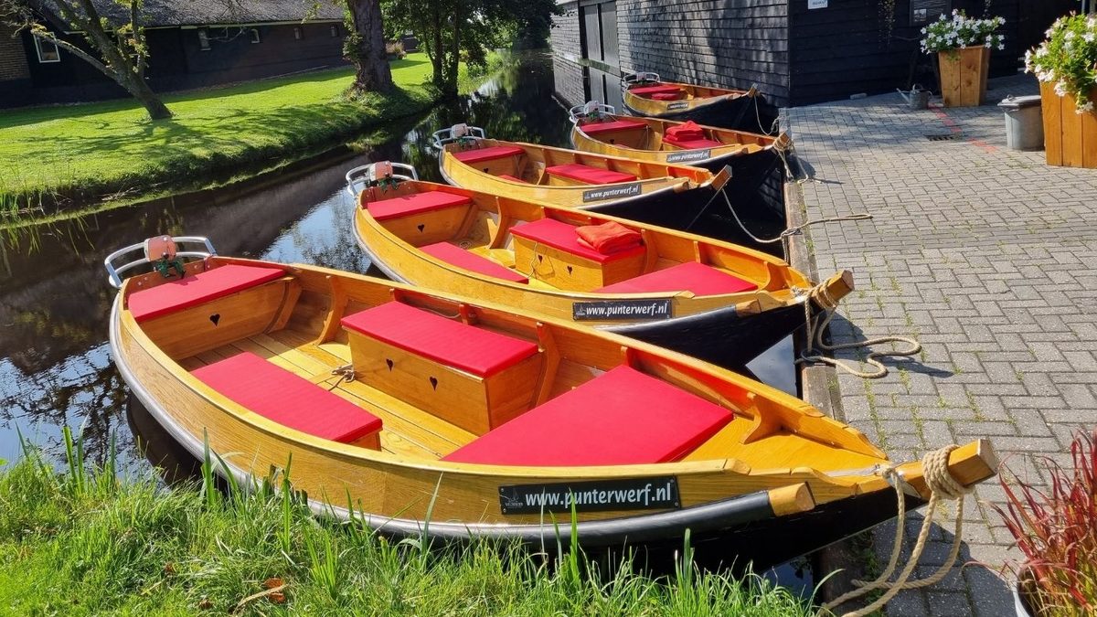 Hölzerne Mietpunter mit roten Kissen am Kai der Punterwerf Wildeboer in Giethoorn