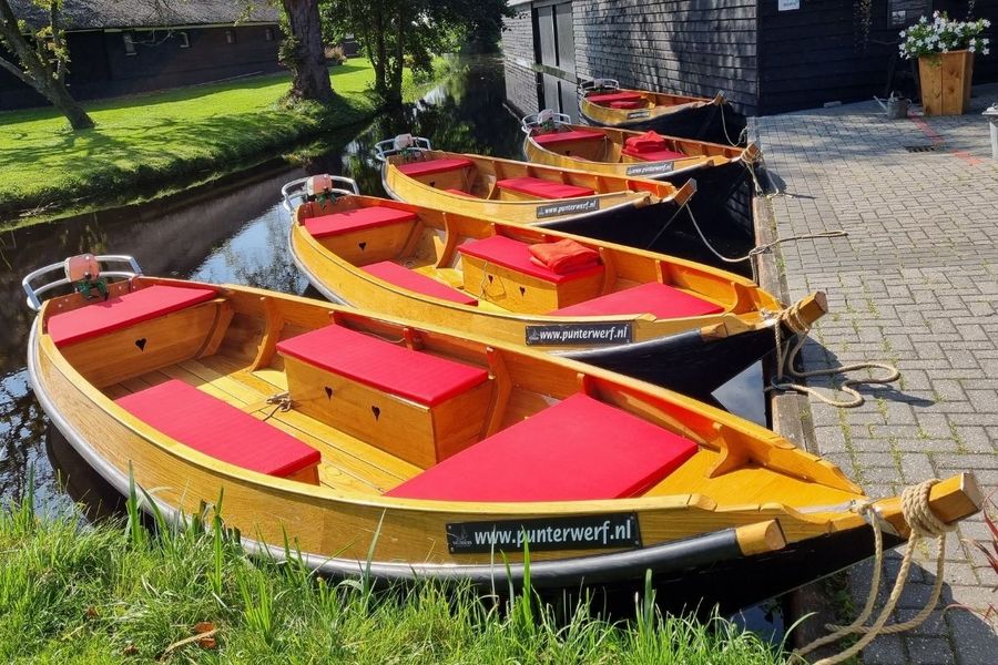 Vier hölzerne Mietpunter mit roten Kissen am Kai der Werft in Giethoorn-Noord