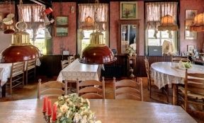 Die Gelagkamer des Restaurants 't Zwaantje mit gedeckten Tischen und Kupferlampen