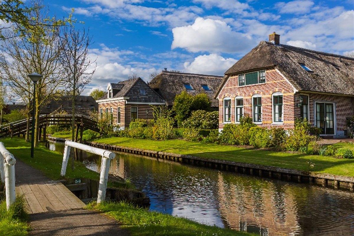 Thatched farmhouse on a canal with a wooden bridge in Giethoorn