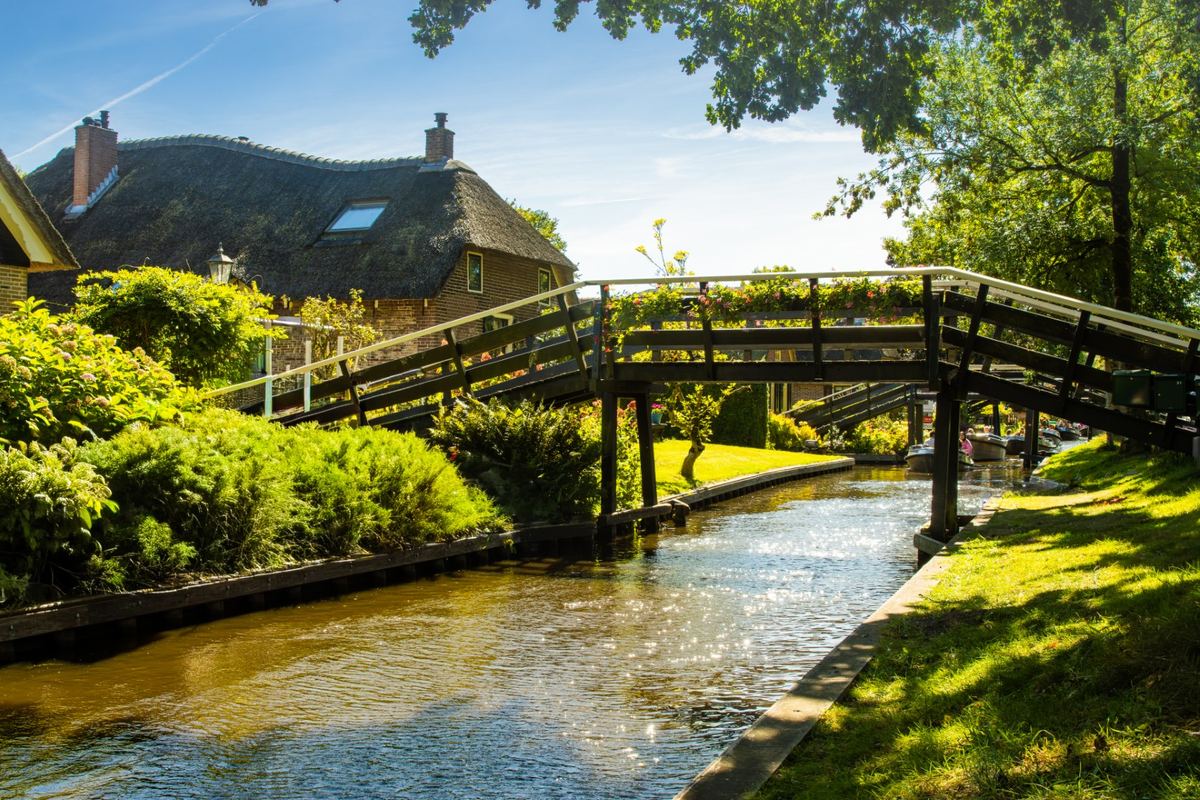 Wooden bridge over a canal by a thatched farmhouse in Giethoorn
