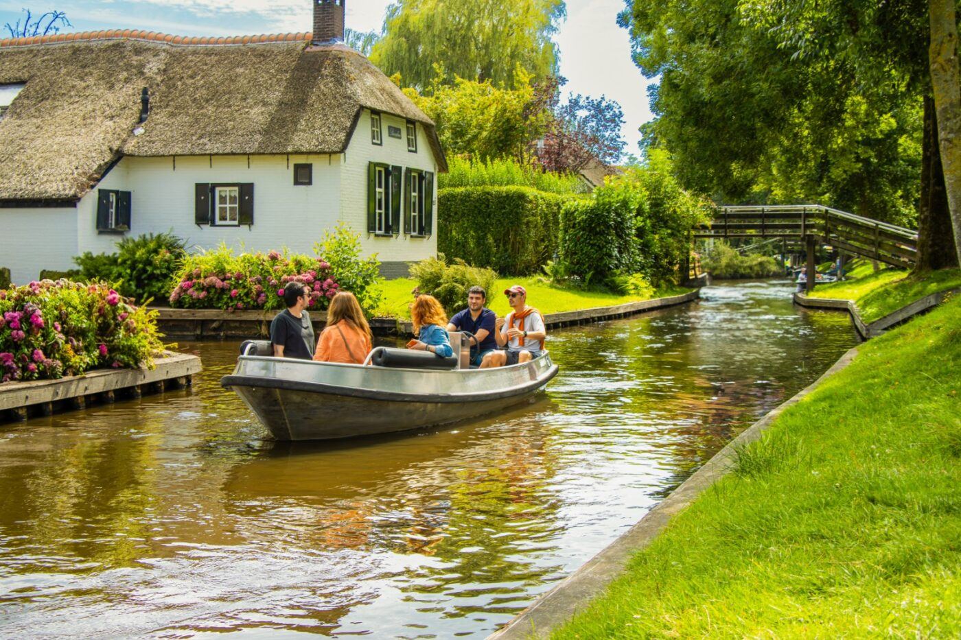 Blick über eine Gracht in Giethoorn mit reetgedeckten Dächern und einem Boot