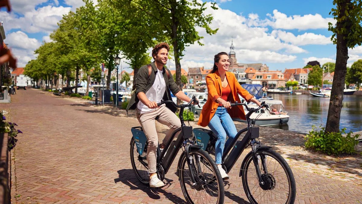 Two people on a shared e-bike by the water in Blokzijl