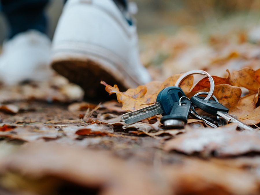 Verlorener Schlüsselbund zwischen Herbstblättern auf einem Weg