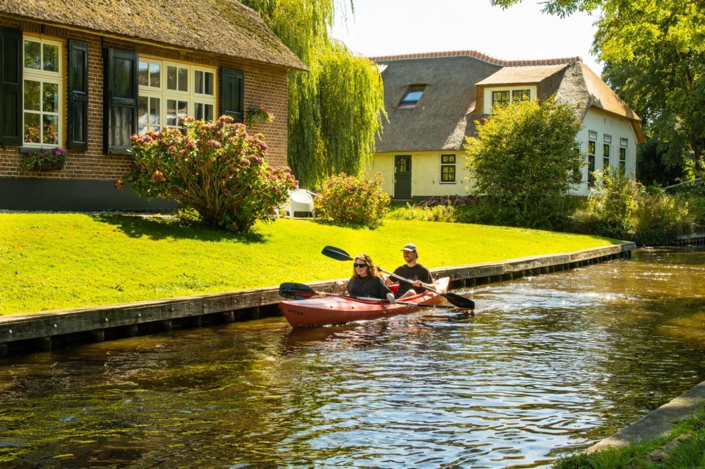 Kanu auf einer Gracht in Giethoorn an einem reetgedeckten Bauernhaus